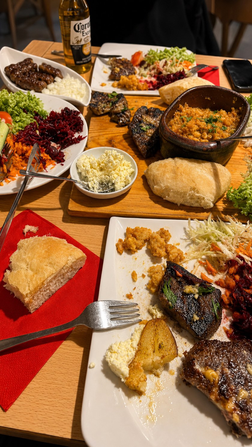 Reich gedeckter Tisch mit Ćevapčići, Salaten, Ajvar und frischem Fladenbrot