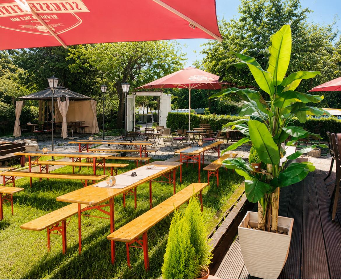 Sonniger Biergarten der Meze Bar mit Bierbänken und Sonnenschirmen