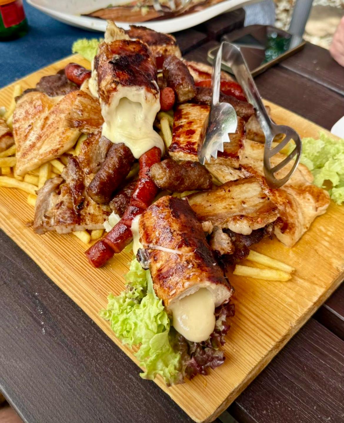Gemischter Grillteller auf Holzbrett mit gefülltem Käse-Fleisch, Würstchen und Pommes