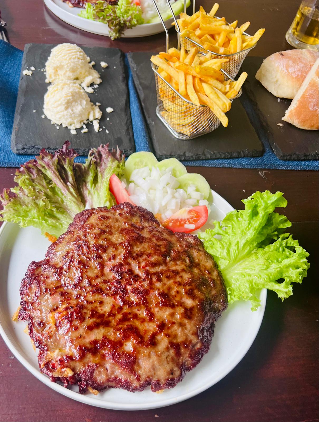 Knusprige Pljeskavica mit Pommes im Körbchen, Salat und Schafskäse
